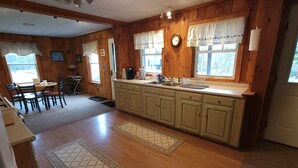 A kitchen with wooden cabinets, a sink, and a dining area with chairs and a table.