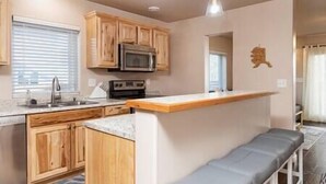 A compact kitchen with wooden cabinets, a microwave, and a built-in bench.