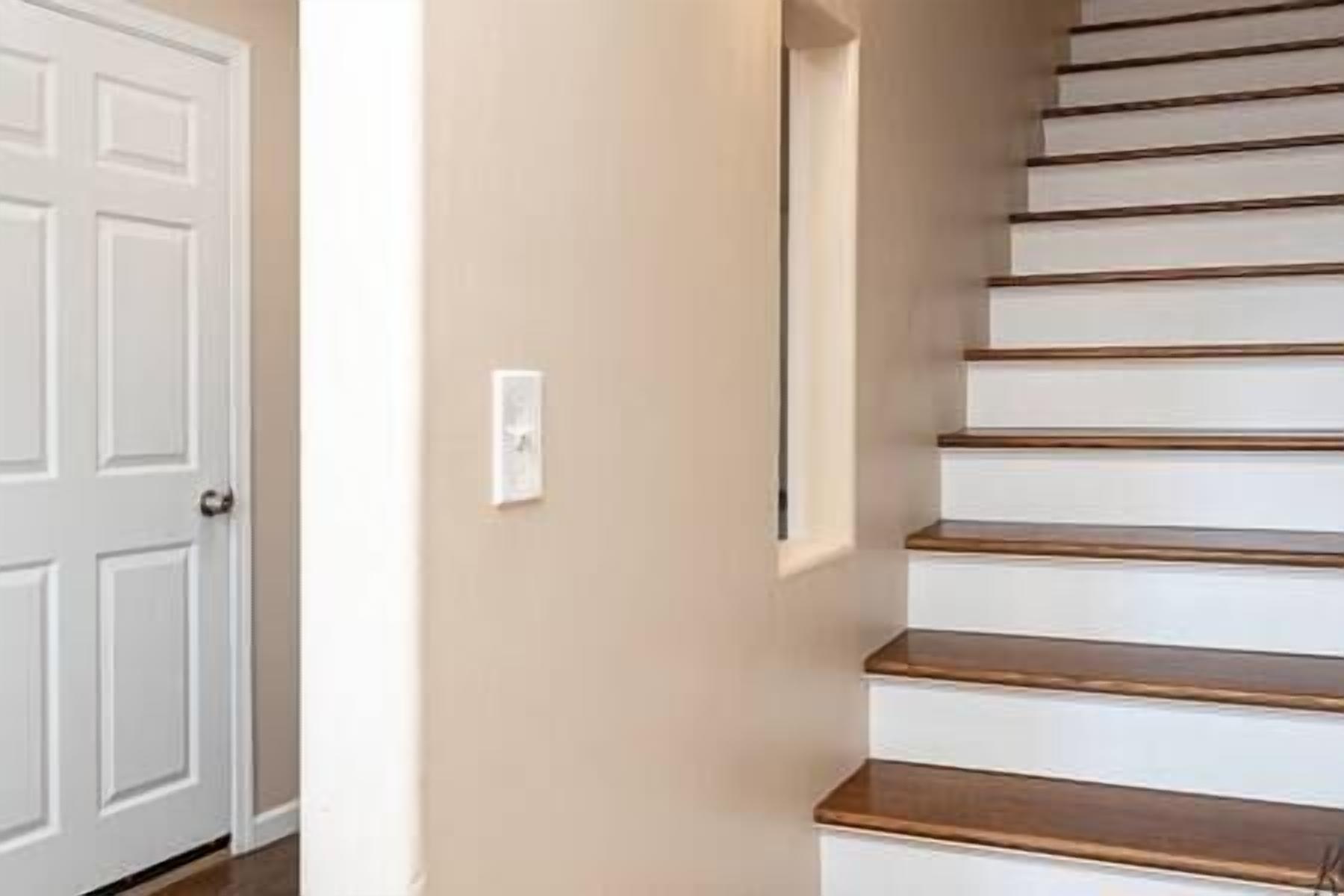 Una escalera con escalones de madera y una puerta blanca.