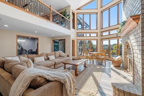 A spacious living area with a large sofa set, a dining table, and a fireplace.