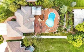 Ein Luftbild eines Anwesens mit Swimmingpool, Sitzgelegenheiten im Freien und einer überdachten Terrasse.
