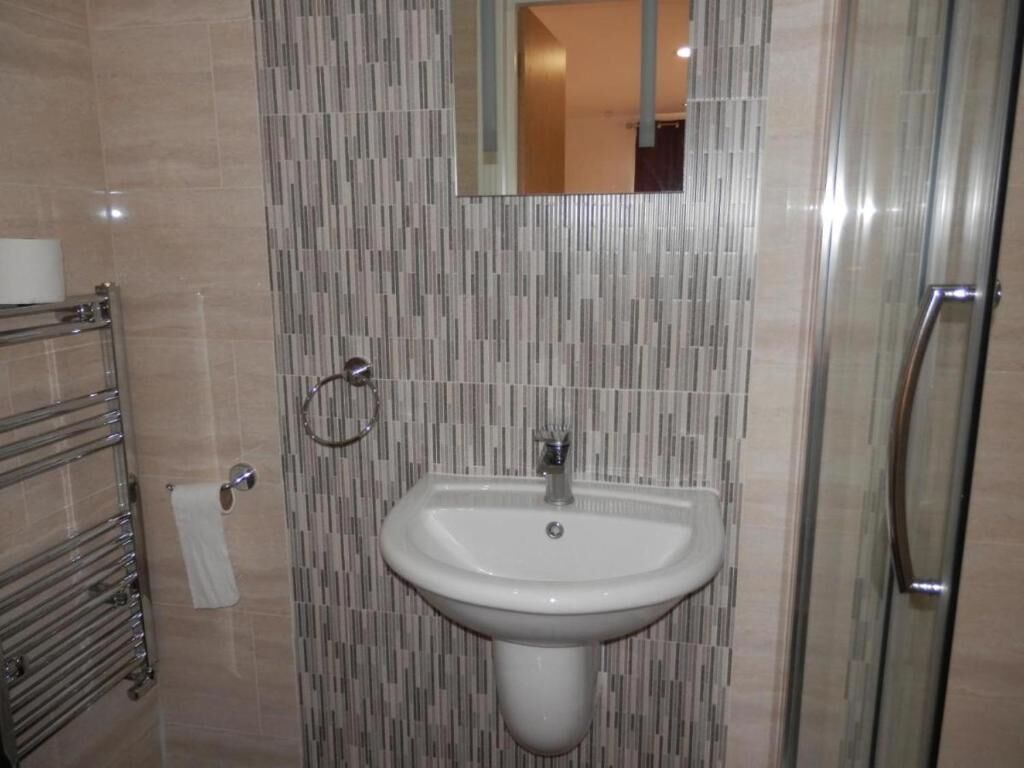 A bathroom with a white sink, a glass shower enclosure, and a towel rack.