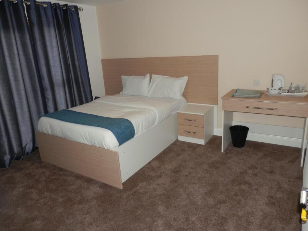 A hotel room with a bed, a desk, and a coffee maker.