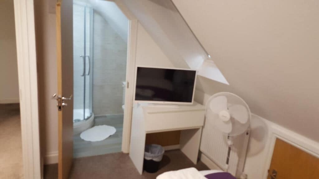 A bedroom with a bed, a TV, and a small desk.