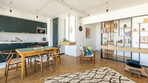 A modern kitchen with dark green cabinets, a wooden dining table, and a herringbone-patterned rug. - Amazing view on Paris, balcony and modern apartment (Paris)