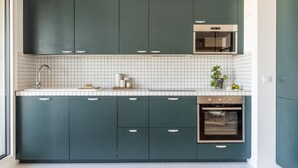 A modern kitchen with teal cabinets, a white tiled backsplash, and a built-in oven. - Amazing view on Paris, balcony and modern apartment (Paris)