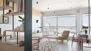 A modern living room with a large window, a dining area, and a bookshelf. - Amazing view on Paris, balcony and modern apartment (Paris)