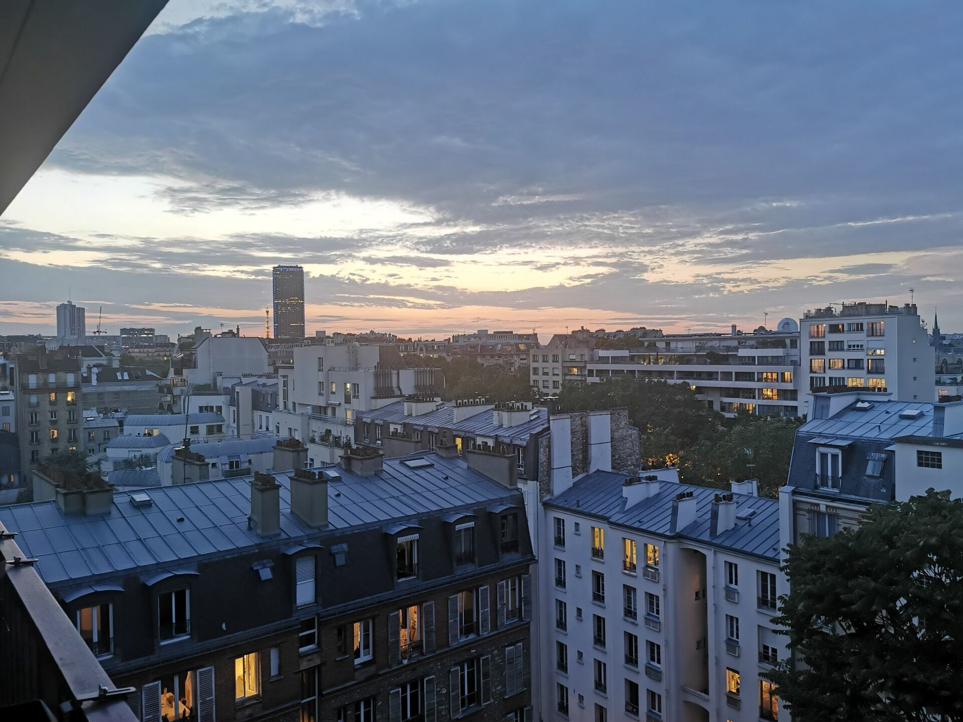 A cityscape at dusk with a mix of residential and commercial buildings, including a prominent tall building in the distance.
