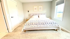 A bedroom with a bed, a nightstand, a wall-mounted lamp, and two framed pictures. - 3 bedroom Townhouse Rooftop Patio & AC (Calgary)
