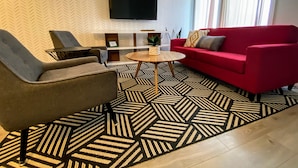 A modern living room with a red sofa, grey armchair, and a coffee table. - 3 bedroom Townhouse Rooftop Patio & AC (Calgary)