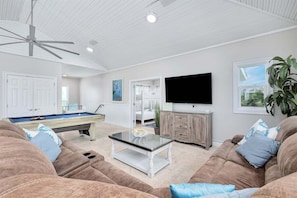 A living room with a pool table, a television, and a ceiling fan.