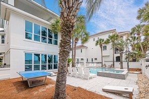 A pool area with lounge chairs, a ping pong table, and a small outdoor table.