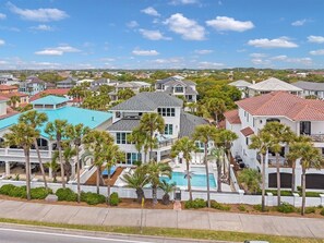 A residential area with multiple houses, a swimming pool, and palm trees.