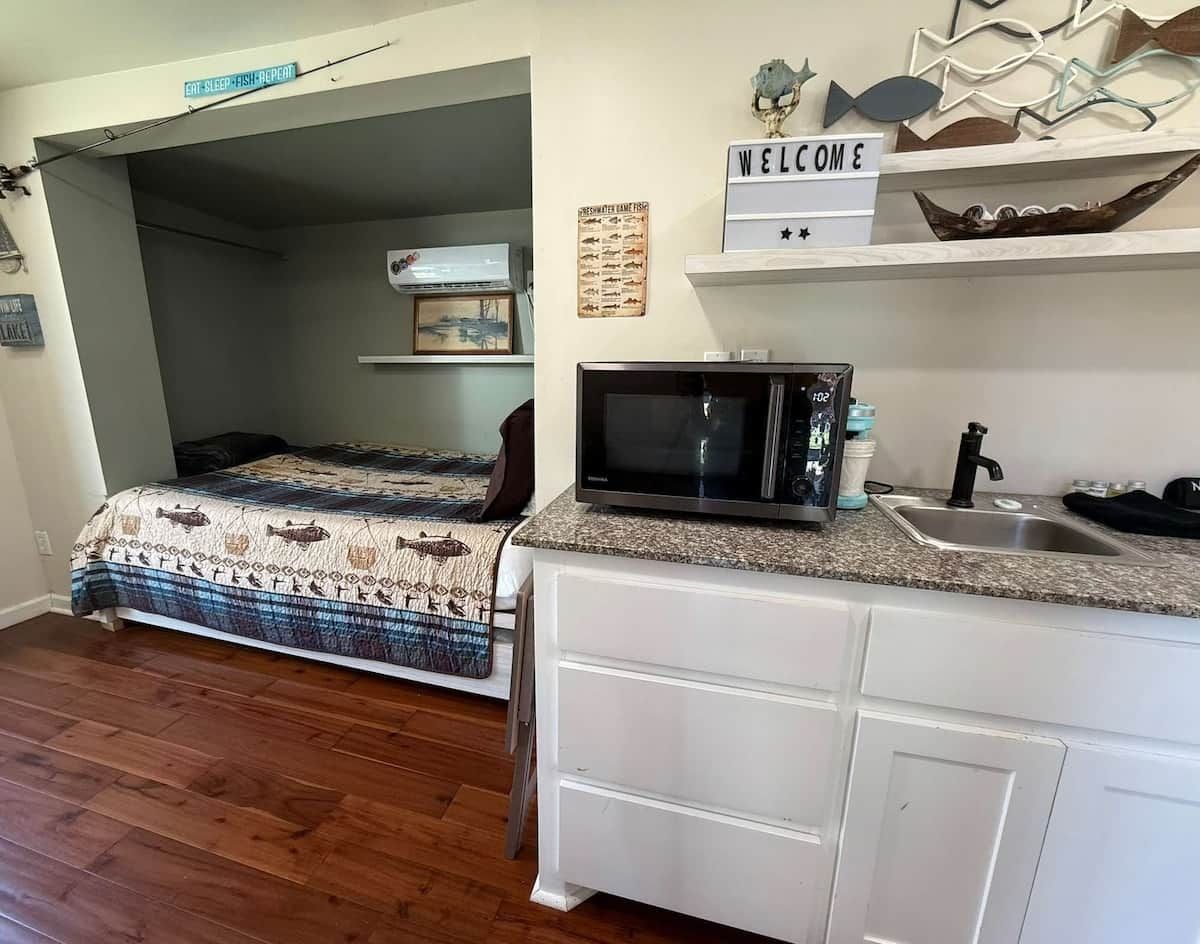 Une chambre compacte comprenant un lit, une petite kitchenette équipée d’un four à micro-ondes et un évier.