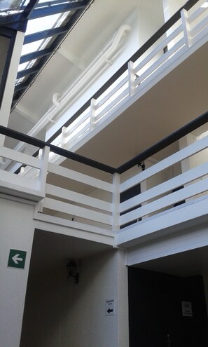 Un edificio de varios niveles con barandas blancas y techo de cristal.