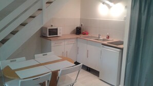 A compact kitchen with white cabinets, a microwave, a coffee maker, and a sink. - Charmant T2 Carcans Lac Proche Plage Avec Terrasse (CARCANS)