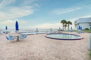 Relax by the ocean with a refreshing dip in the pool surrounded by lounge chairs and umbrellas.