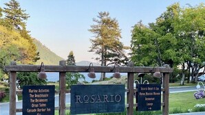 Un panneau indicateur avec le mot « ROSARIO » au centre, flanqué d’autres panneaux indiquant « Activités nautiques », « The Beachhouse », « The Residences », « Orcas Suites » et « Cascade Harbor Inn ».