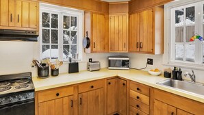 A kitchen with wooden cabinets, a stove, a microwave, and a window with a view of snow outside. - 4 BR Antique Provincetown Single Family Home in the Center of Town - Sleeps 9! (Provincetown)