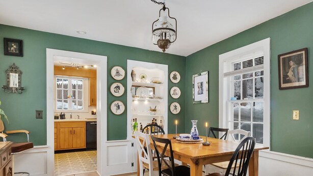 A dining area with a wooden table and chairs, a chandelier, and a view of the kitchen through an open door. - 4 BR Antique Provincetown Single Family Home in the Center of Town - Sleeps 9! (Provincetown)