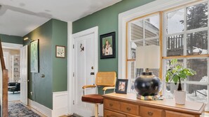A room with green walls, a wooden dresser, a chair, a lamp, and a potted plant. - 4 BR Antique Provincetown Single Family Home in the Center of Town - Sleeps 9! (Provincetown)