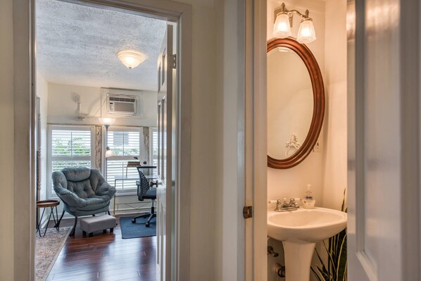 Relax in a comfortable space with a tufted armchair and a small table, featuring a large window and a stylish mirror.