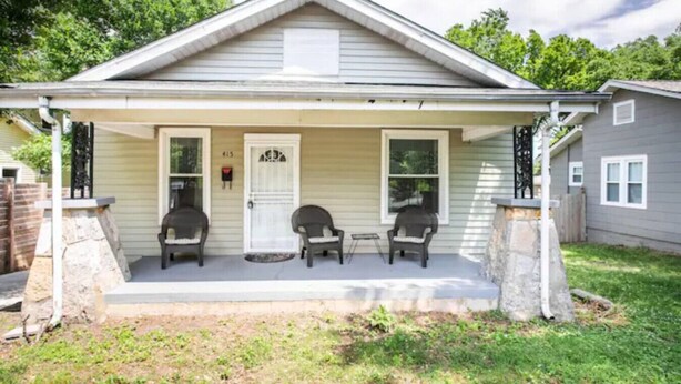 A single-story house with a covered porch, two chairs, and a mailbox.