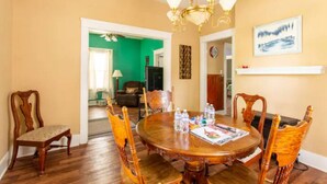A dining room with a wooden table and chairs, a chandelier, and a green wall in the background.
