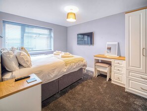 A bedroom with a bed, bedside table, desk, chair, wardrobe, and a TV.