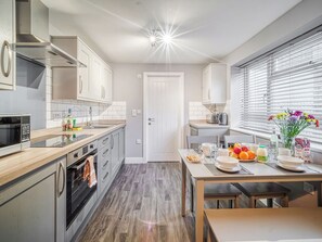 Eine moderne Küche mit Essbereich, ausgestattet mit Backofen, Mikrowelle und einem Fenster mit Jalousien.