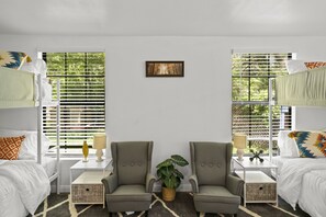 A room with bunk beds, two armchairs, a small table with a lamp, and a picture on the wall. - Magnolia House w/ 4 Beds 2 Baths on 1.5 Acres ⭐ (Magnolia)