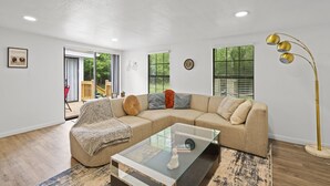 A modern living room with a sectional sofa, a glass coffee table, and a floor lamp. - Magnolia House w/ 4 Beds 2 Baths on 1.5 Acres ⭐ (Magnolia)