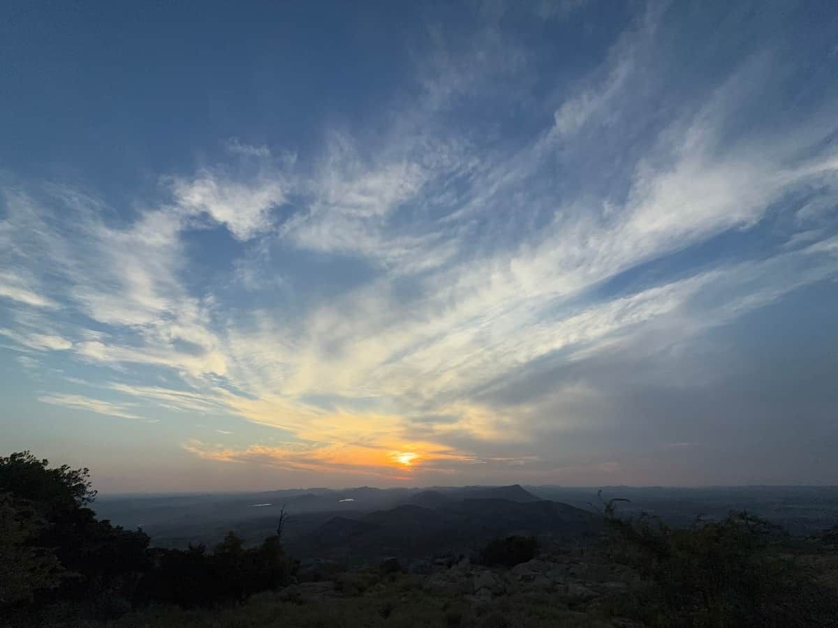 A landscape with a clear sky and a setting sun.