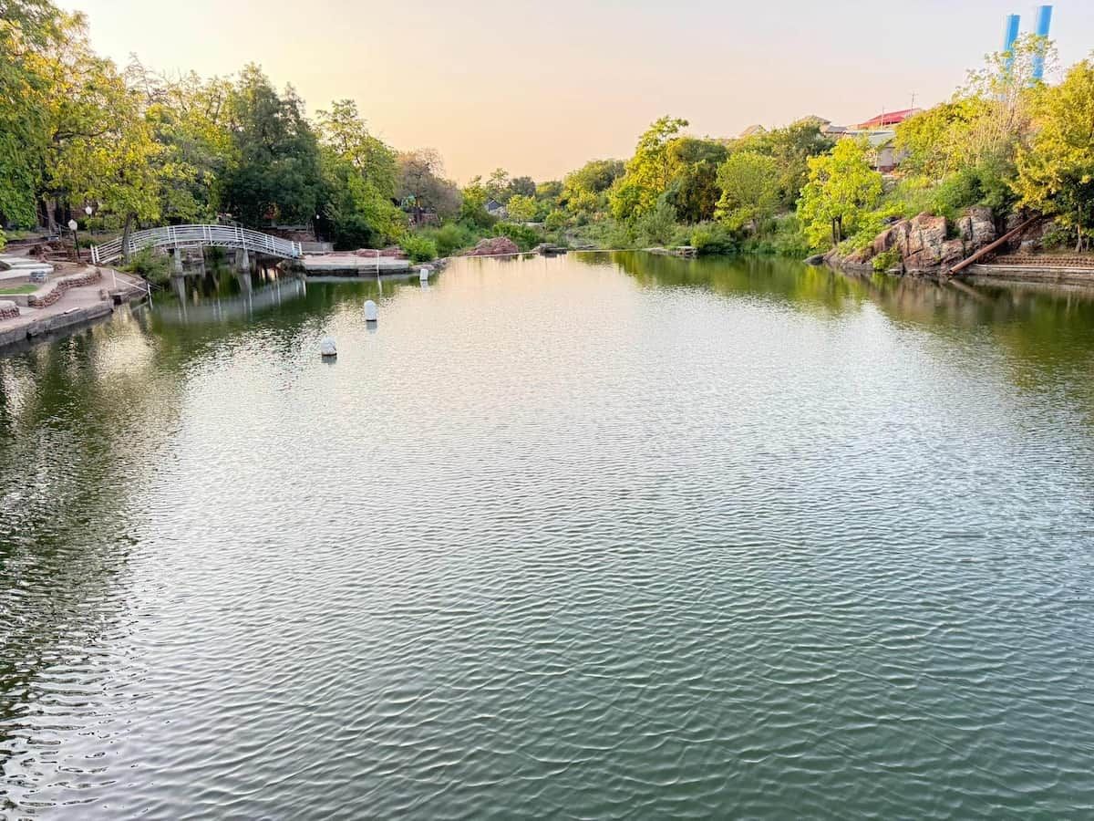 A calm river with a bridge and trees on the banks.