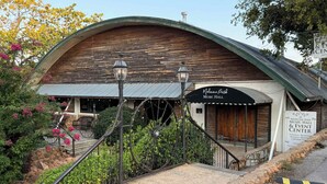 Um edifício rústico com telhado curvo e uma placa com a inscrição 'Medicine Park Music Hall & Event Center'.
