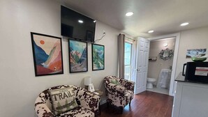 Uma sala de estar com dois sofás, uma televisão montada na parede e quadros decorativos.