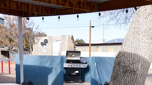 An outdoor barbecue area with a grill, tables, and a tree.