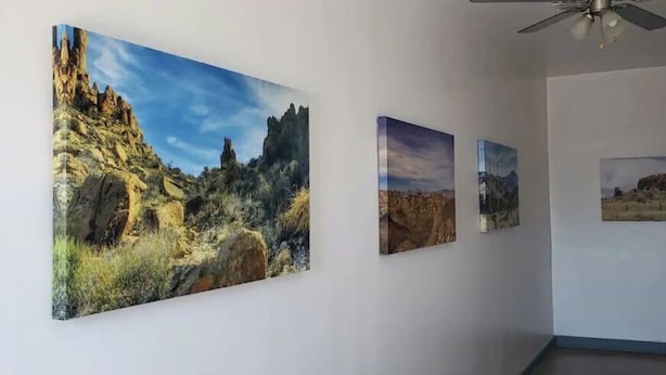 A hallway with four framed landscape paintings on the wall.