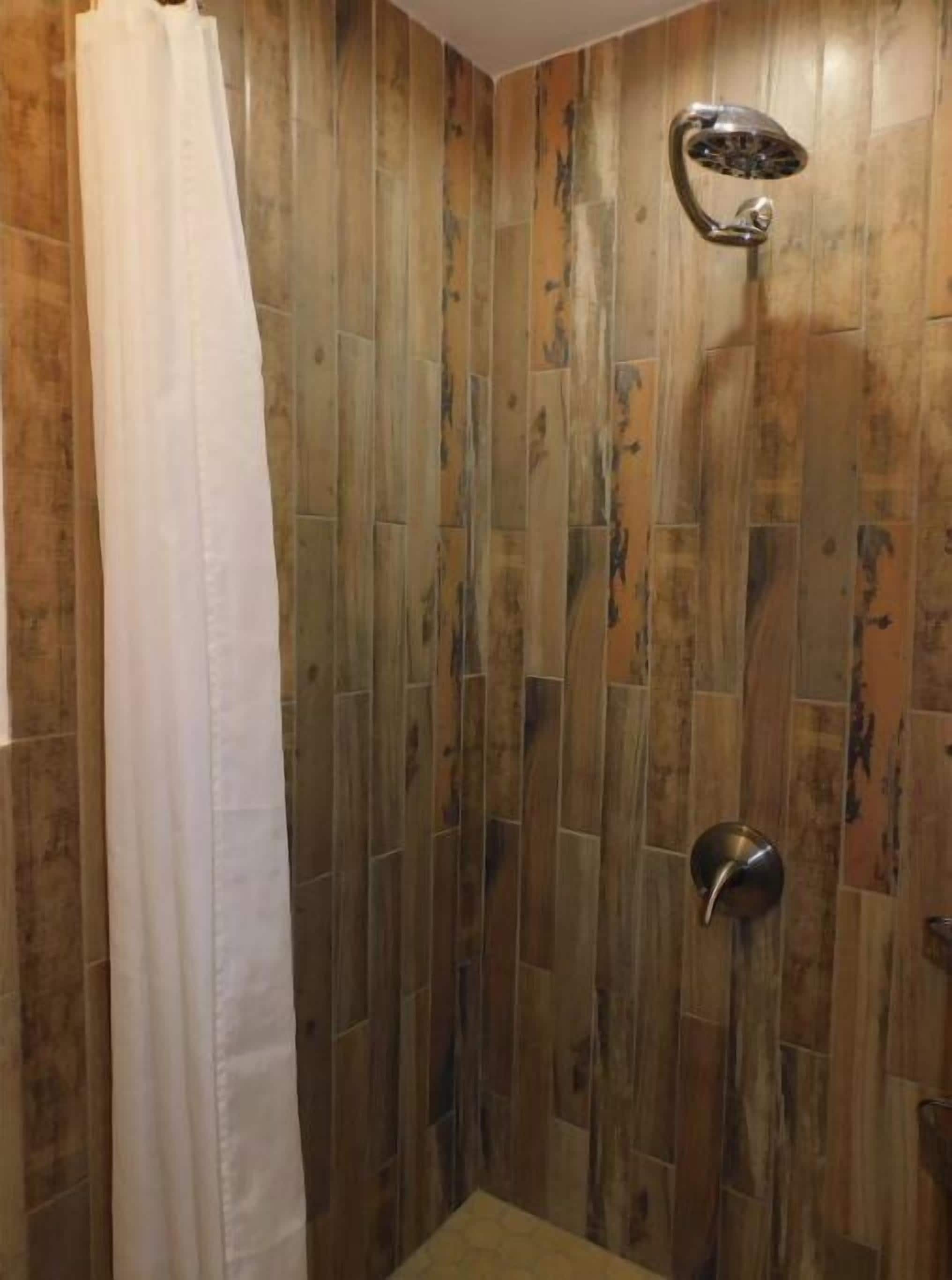 Un espace douche avec un revêtement mural en bois et un pommeau de douche.