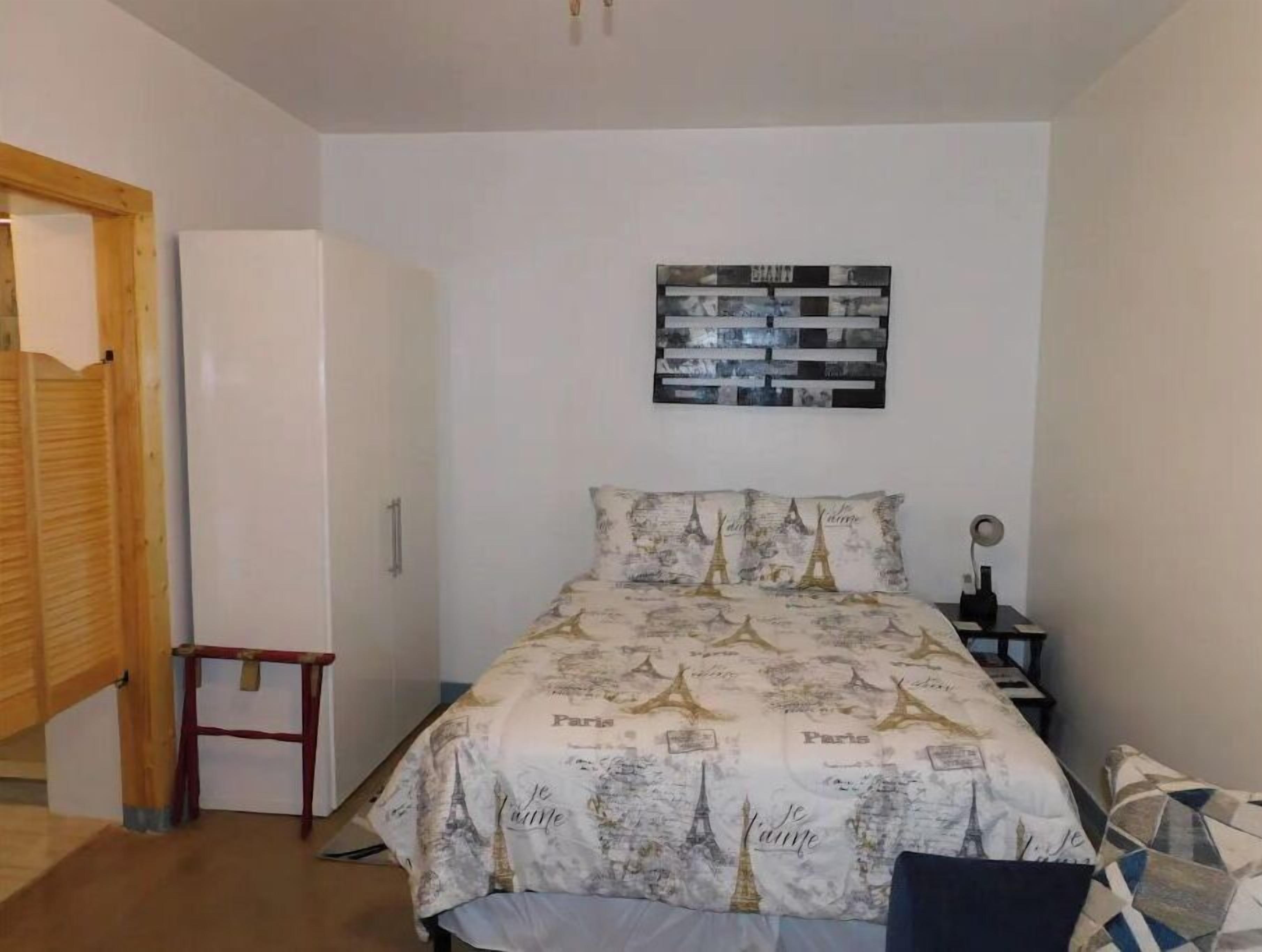 A bedroom with a bed, a small table, a chair, and a wardrobe.