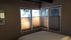 A bedroom with a bed, a window with blinds, and a framed picture on the wall. - Bootlegger Cove House - Downtown Anchorage (Anchorage)