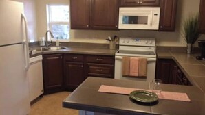 A kitchen with dark wooden cabinets, a white refrigerator, a microwave, and a stove. - Bootlegger Cove House - Downtown Anchorage (Anchorage)