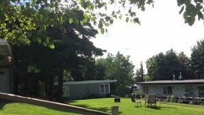 A fenced yard with a grassy area, a small building, and trees. - Bootlegger Cove House - Downtown Anchorage (Anchorage)