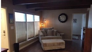 A living room with a sofa, ottoman, and a rug. - Bootlegger Cove House - Downtown Anchorage (Anchorage)