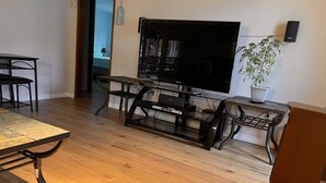 Ett modernt vardagsrum med en platt-TV, ett matbord och en krukväxt.