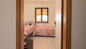 Ein Schlafzimmer mit zwei Betten, einem Fenster und einer Heizung.