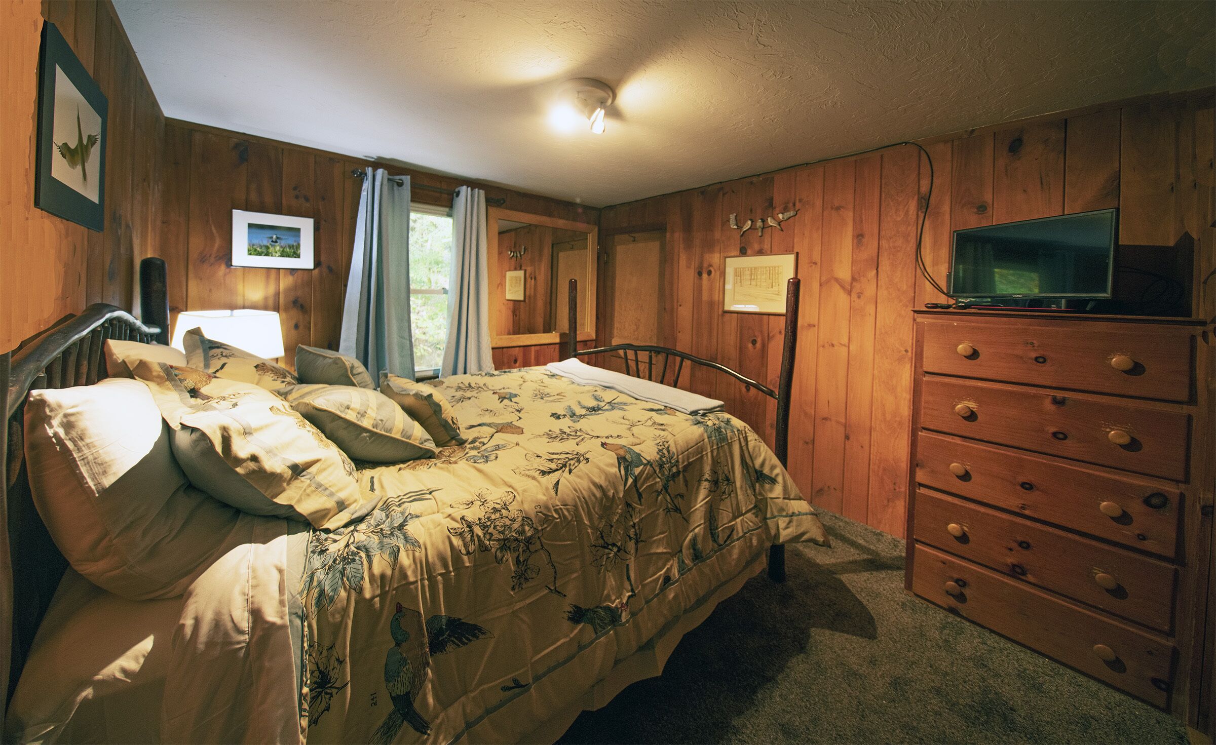 Een slaapkamer met een houten bed, een dressoir en een televisie.