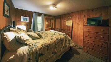 Een slaapkamer met een houten bed, een dressoir en een televisie.