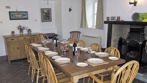 A dining room with a long wooden table set for a meal, surrounded by wooden chairs. - 4 bedroom accommodation in Grassington (Grassington)