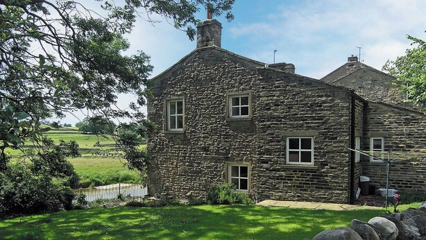 A stone house with a grassy yard and a stone wall in the foreground. - 4 bedroom accommodation in Grassington (Grassington)